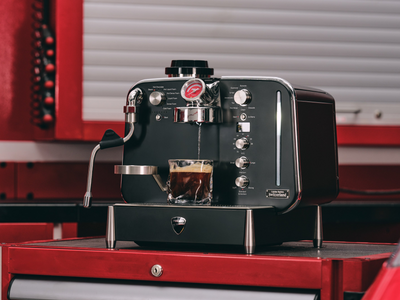 Barista M3 in black on a red workshop trolley, pouring espresso into a clear glass cup