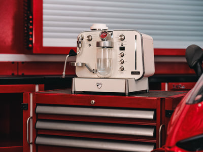 Barista M3 in white on a red garage tool chest with a glass carafe in place under the brew head