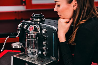 Black Barista M3 with a glass jug standing on the drip tray as a woman looks on from the side