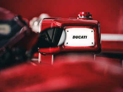 White Ducati number-plate badge on the glossy red rear panel, shot with very shallow focus