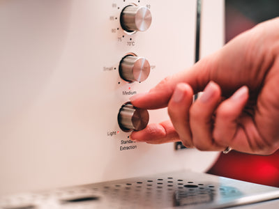 Fingertips on the Light-to-Strong extraction dial of the white Barista M3