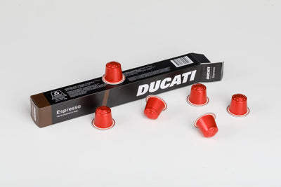 Caja Espresso by Ducati tumbada, rodeada de cápsulas rojas compatibles con Nespresso® Original