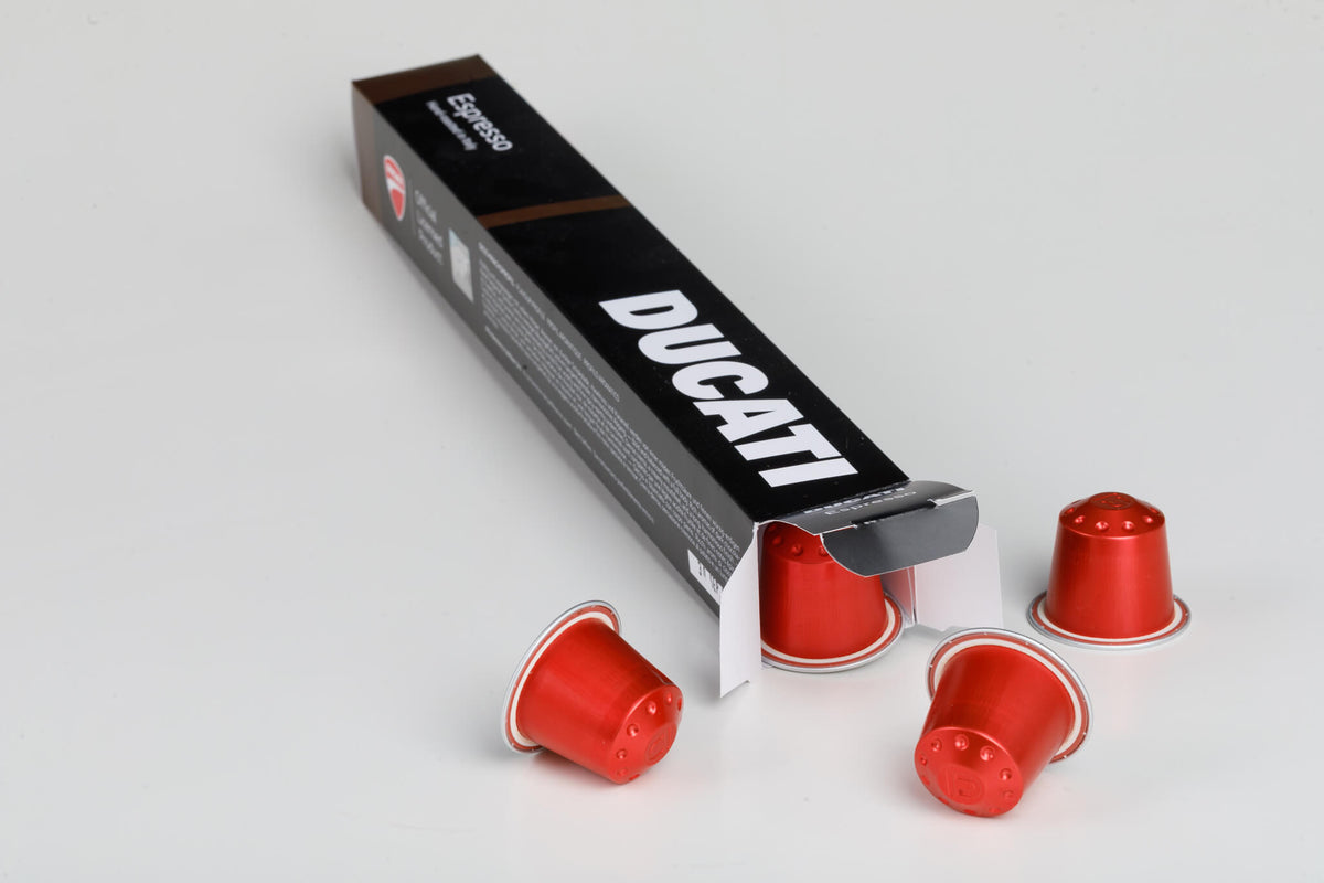 Caja Espresso by Ducati abierta de la que salen cápsulas rojas para Nespresso® Original